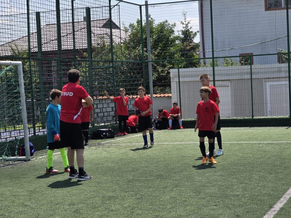 Grupa 2015–2016 în acțiune, pasând mingea în timpul unui meci animat la un eveniment comunitar de fotbal din București.