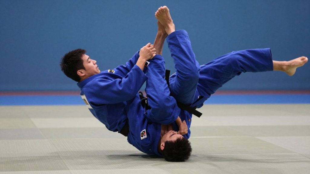 Judoka efectuând o tehnică de aruncare pe saltea.