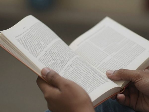 Mâini ținând un jurnal medical deschis.