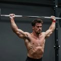 Halterofil ridicând o bară grea deasupra capului.