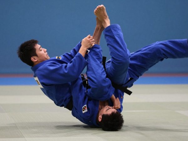 Judoka efectuând o tehnică de aruncare pe saltea.